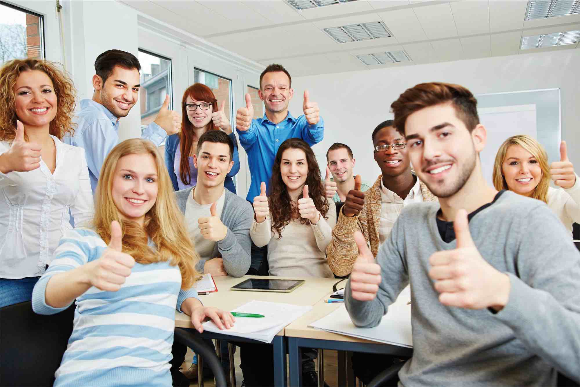 Native English speaking teachers and students giving thumbs up in a classroom in Linz, Austria